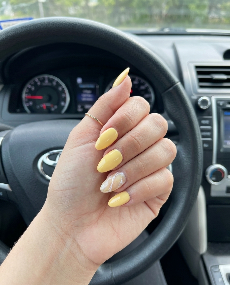 Butter Yellow Marble Almond Nails 2026 Butter yellow almond nails with white marble accent for fair skin. Chic summer nails 2026.