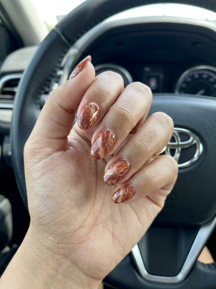 Bohemian orange summer nails 2026 with terracotta marble effect and gold veining on short nails.