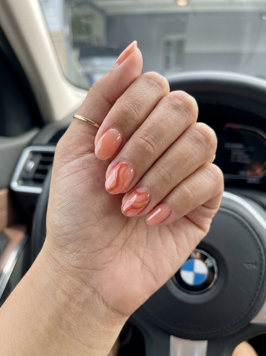 Peach fuzz jelly short oval summer nails 2026 with coral swirls for date night.