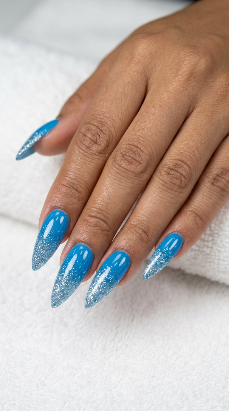 Sparkling cerulean fade stiletto nails for festivals and parties. Blue to silver glitter ombre effect.